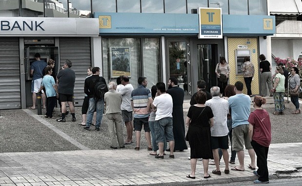 Oamenii stau la coadă pentru a folosi bancomate în Atena.