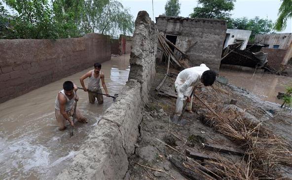 Oameni afectaţi de inundaţii încearcă să oprească avansarea apelor de inundaţie în locuinţele lor din Peshawar, Pakistan, 2 august 2015.