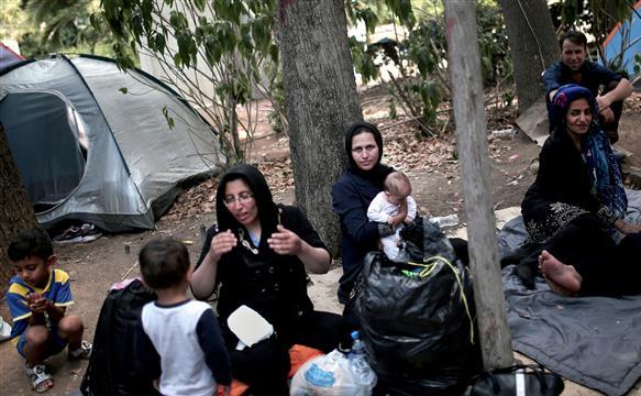 Refugiaţii se adună în faţa corturilor ridicate într-un parc central din Atena, 7 august 2015.