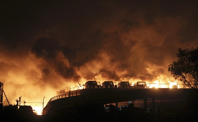 Mai multe maşini sunt văzute arzând dupa exploziile care au zguduit depozitul de produse inflamabile din oraşul chinez Tianjin, 12 august 2015.