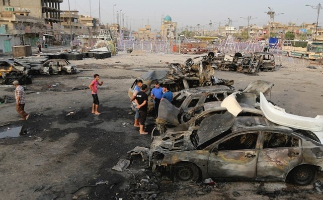 Civilii inspectează locul exploziei unei maşini capcană în cartierul Sadr City din Bagdad, 6 august 2015. (Captură Foto)