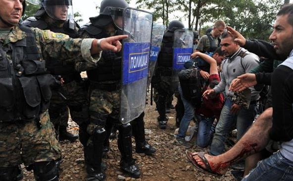 Imigranţii transportă o persoană rănită în timpul ciocnirilor cu poliţia macedoniană în apropiere localitatea Idomeni de la graniţa dintre Grecia şi Macedonia, 21 august 2015. 