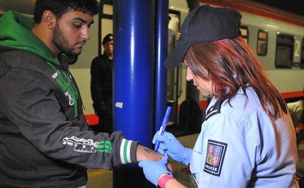 O poliţistă cehă marchează braţul unui refugiat cu un număr de identitate.