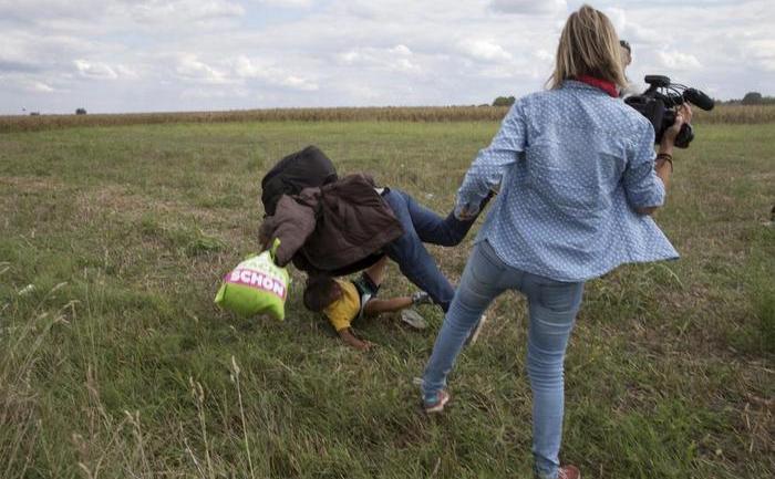 O femeie cameram pune piedică unui refugiat ce fuge de poliţie în satul Roszke. Bărbatul avea în braţe un copil.