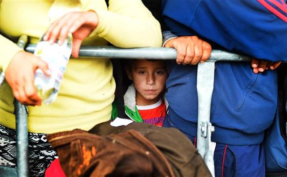 Un băiat aşteaptă împreună cu alţi refugiaţi să se îmbarce într-un autobuz în Nickelsdorf,  Austria, în apropiere de graniţa cu Ungaria, 10 septembrie 2015.