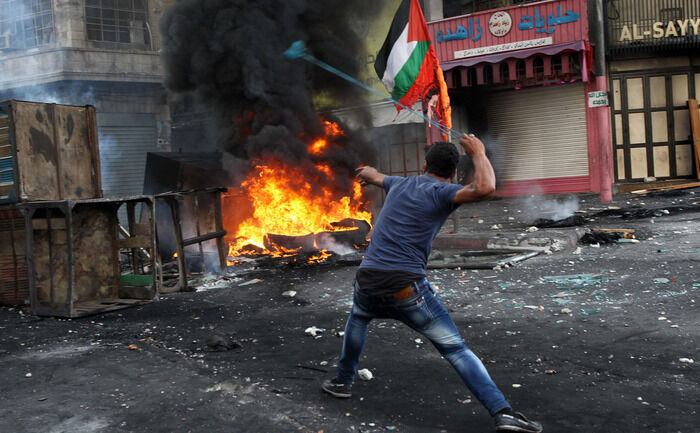 Palestinian aruncând cu pietre împotriva unui soldat israelian (Hazem Bader/AFP/Getty Images)