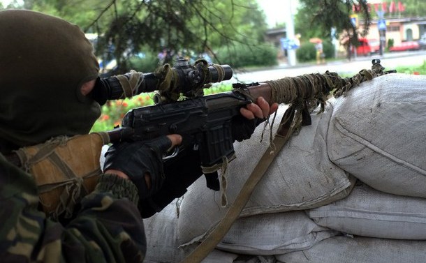Un separatist pro-rus se uită prin lentilele puştii sale la un punct de control din oraşul ucrainean Doneţk.