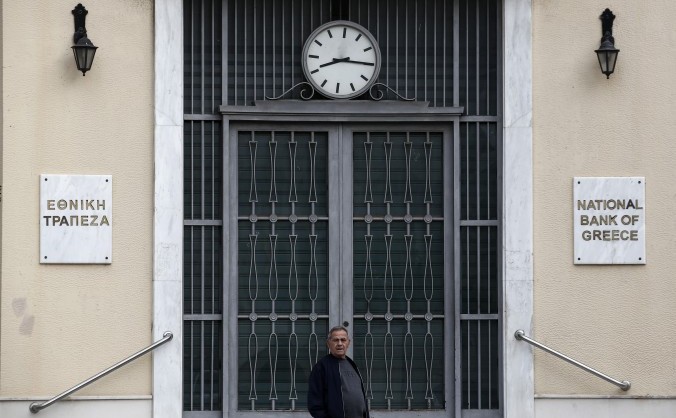 Un barbat stă în faţa unei filiale a Băncii Naţionale în Piraeus, în apropiere de Atena, 31 octombrie 2015.