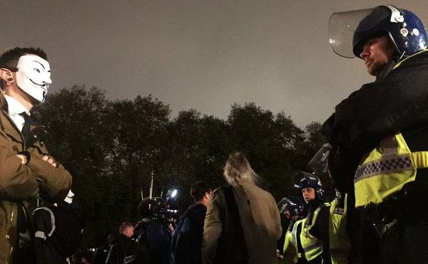 Un manifestant anti-capitalism stă în faţa unui cordon de poliţişti în Londra, 5 noiembrie 2015.