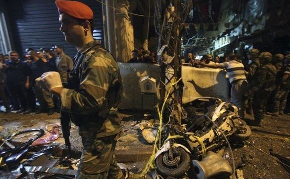 Rezidenţi şi membri ai armatei libaneze inspectează locul a două explozii în suburbiile sudice al Beirutului, 12 noiembrie 2015.
