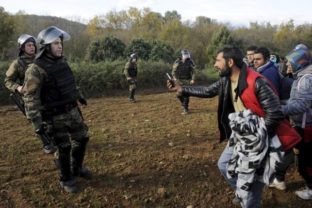 Ofiţeri de poliţie macedoneni opresc imigranţii să treacă graniţa dintre  Grecia şi Macedonia în apropiere de localitatea macedoneană Gevgelija, 2  decembrie 2015.