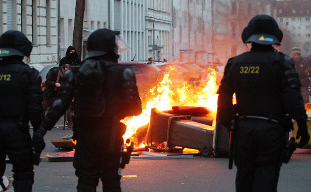 Poliţiştii stau în faţa unor containere incendiate în timpul ciocnirilor violente cu un grup de manifestanţi care se opun unui marş neo-nazist în orasul german Leipzig, 12 decembrie 2015.