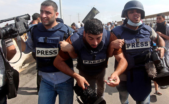 Jurnalişti palestinieni îşi ajută un coleg rănit după ce au fost atacaţi de soldaţi israelieni în apropierea punctului de frontieră Erez, 13 octombrie 2015.