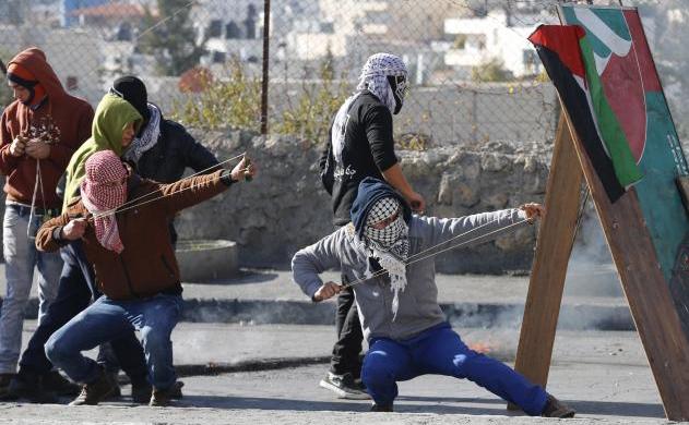 Tineri manifestanţi palestinieni folosesc praştii pentru a arunca pietre asupra trupelor israeliene în timpul unor încleştări în oraşul Betleem din Cisiordania, 13 ianuarie 2016.