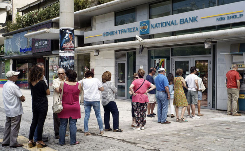 Cetăţeni greci stau la coadă pentru a scoate bani de la bancomat.