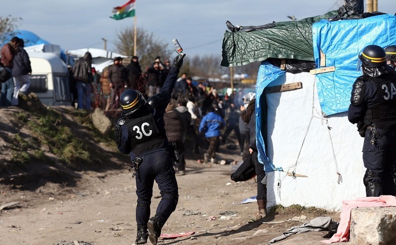 Un ofiţer de poliţie aruncă o grenadă cu gaz lacrimogen în “jungla” din Calais, 29 februarie 2016.