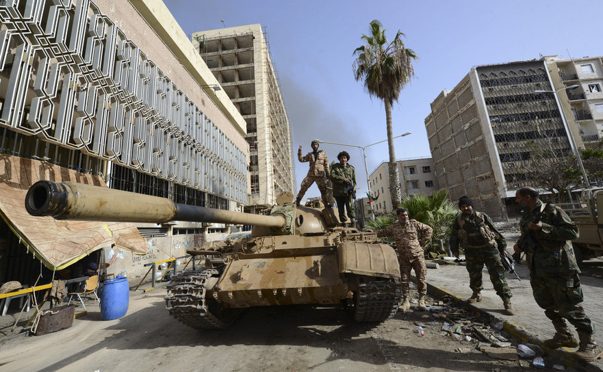 Membri ai forţelor pro-guvernamentale stau lângă un tanc în apropierea portului Benghazi.