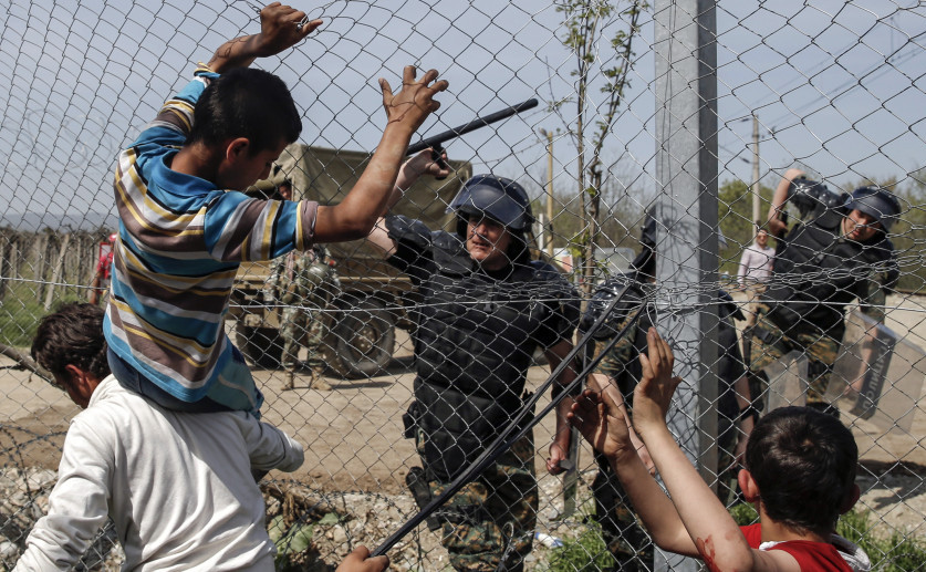 Un poliţist macedonean îşi foloseşte bastonul pentru a împiedica imigranţii şi refugiaţii să deschidă un gard de frontieră în apropiere de satul elen Idomeni, 7 aprilie 2016.