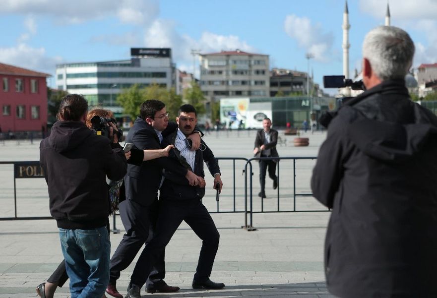 Un bărbat înarmat este oprit de forţele de ordine după ce a tras înspre jurnalistul Can Dunar în faţa Palatului Justiţiei din Istanbul, 6 mai 2016.
