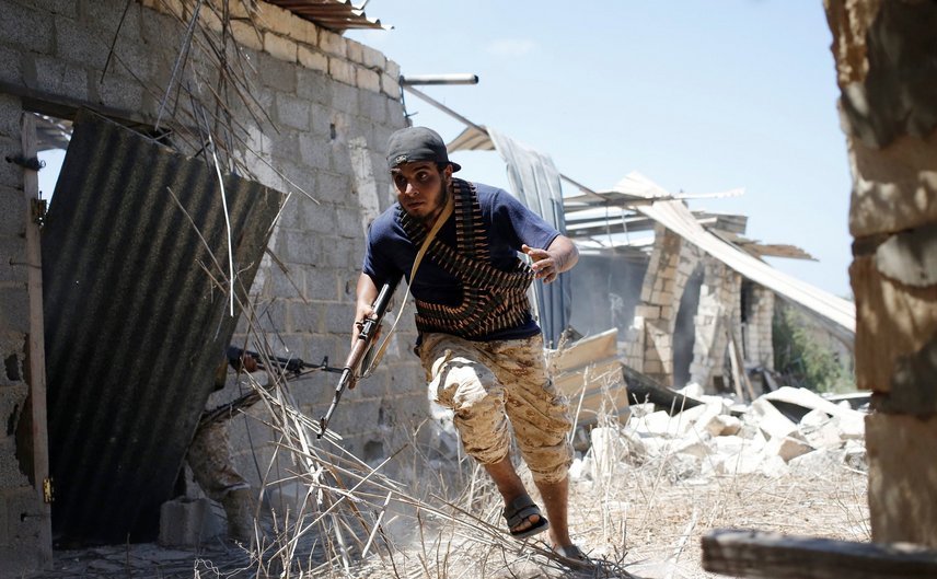 Un luptător din forţele libiene aliate Guvernului de Acord Naţional, care este susţinut de ONU, se adăposteşte în timpul unei bătălii cu jihadiştii Statului Islamic în oraşul Sirte, Libia, 31 iulie 2016.
