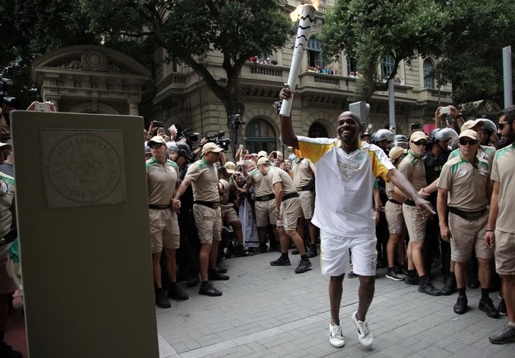 Măturătorul de stradă Street Renato Sorriso poartă Ţorţa Olimpică după sosirea acesteia în Rio de Janeiro, 3 august 2016.