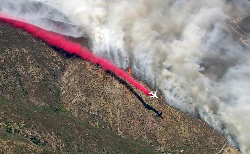 Un avion lansează substanţe ignifuge pentru a încearca să oprească avansarea unui incendiu de vegetaţie în California, SUA, 16 august 2016.