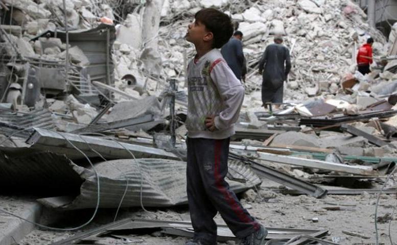 Un copil stă printre clădirile bombardate în oraşul sirian Alep.