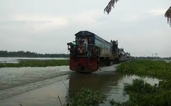 
Bangladesh: trenul traversează câmpurile de orez pe un drum complet inundat, dând senzaţia că circulă pe apă