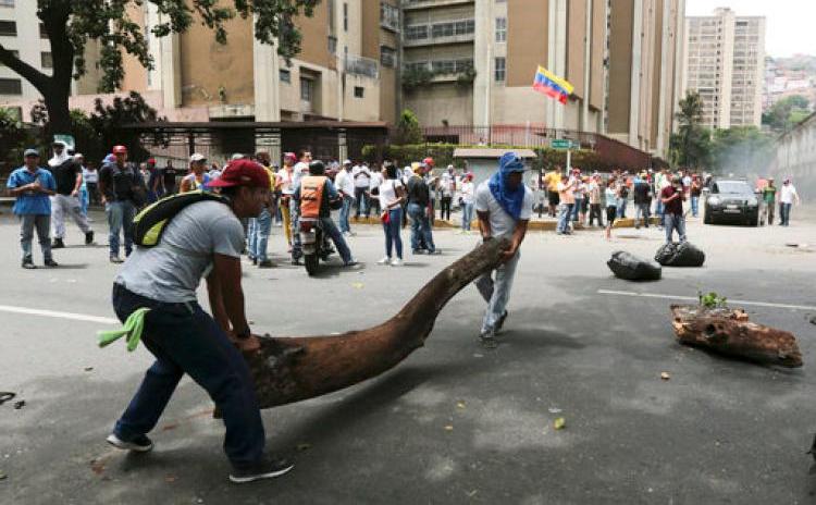 Membri ai opoziţiei ridică o baricadă în timpul unui protest anti-guvern în Caracas, Venezuela, 19 aprilie 2017.