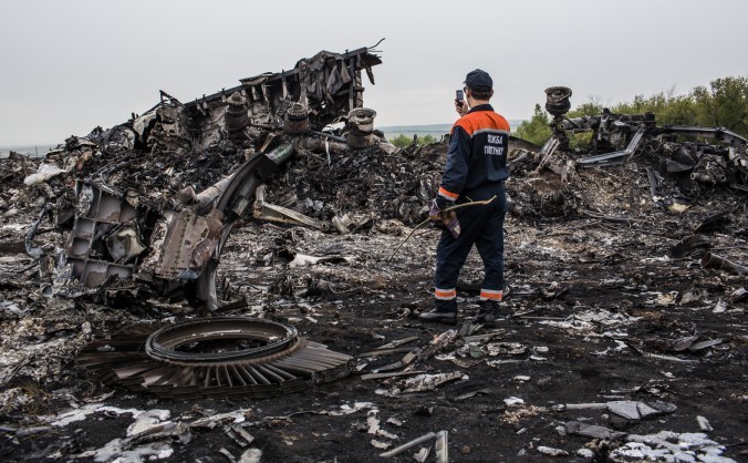 Un angajat al serviciilor de urgenţă fotografiază, în 18 iulie 2014, rămăşiţe ale zborului malaezian MH17, care fusese doborât cu o zi înainte în estul Ucrainei.