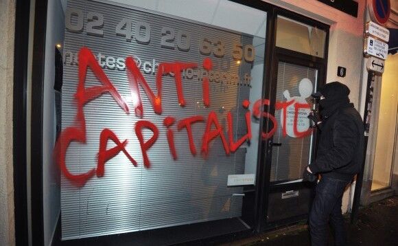 Un membru al  grupului extremist Antifa vandalizează un magazin din Nantes, Franţa, pe  14 februarie 2014 (FRANK PERRY / AFP / Getty Images)