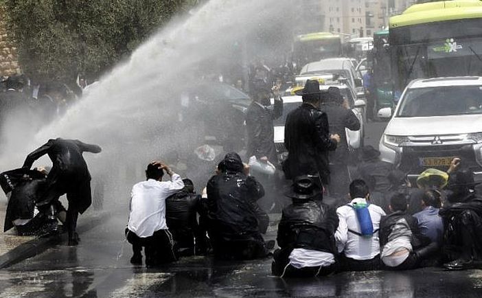 Bărbaţi ultra-ortodocşi sunt atacaţi cu tunuri cu apă de forţele de securitate în timpul unui protest, desfăşurat în Ierusalim, împotriva arestării unei persoane care a evitat înrolarea în serviciul militar, 2 august 2018.