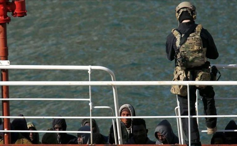 Un soldat al forţelor speciale malteze păzeşte un grup de imigranţi la bordul petrolierului El Hiblu 1