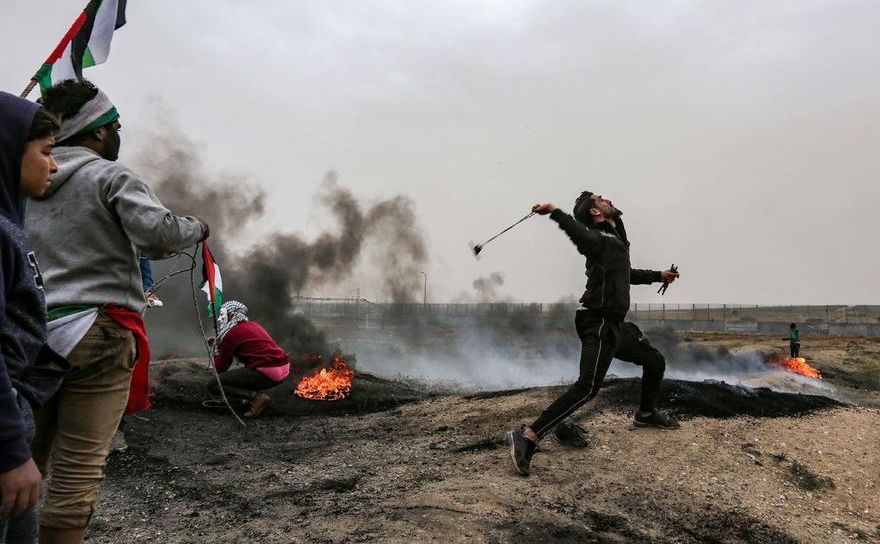 Manifestant palestinian foloseşte o praştie pentru a arunca o piatră către forţele israeliene în timpul protestelor de la graniţa dintre Fâşia Gaza şi Israel în 30 martie 2019
