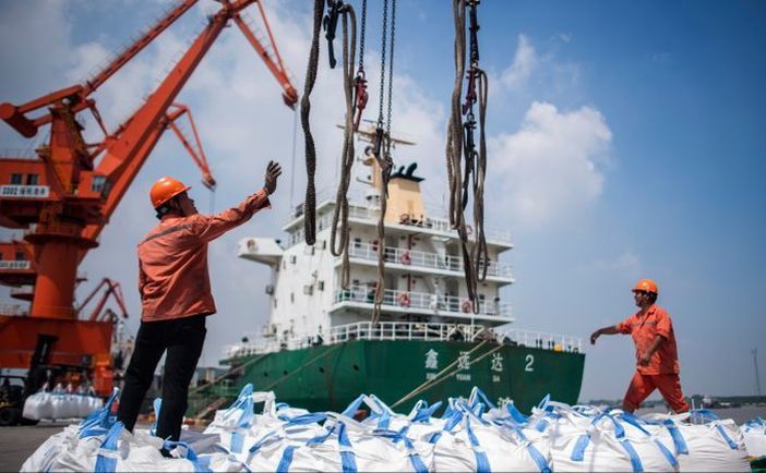 Muncitori descarcă saci cu chimicale într-un port din Zhangjiagang, provincia estică chineză Jiangsu, 7 august 2018