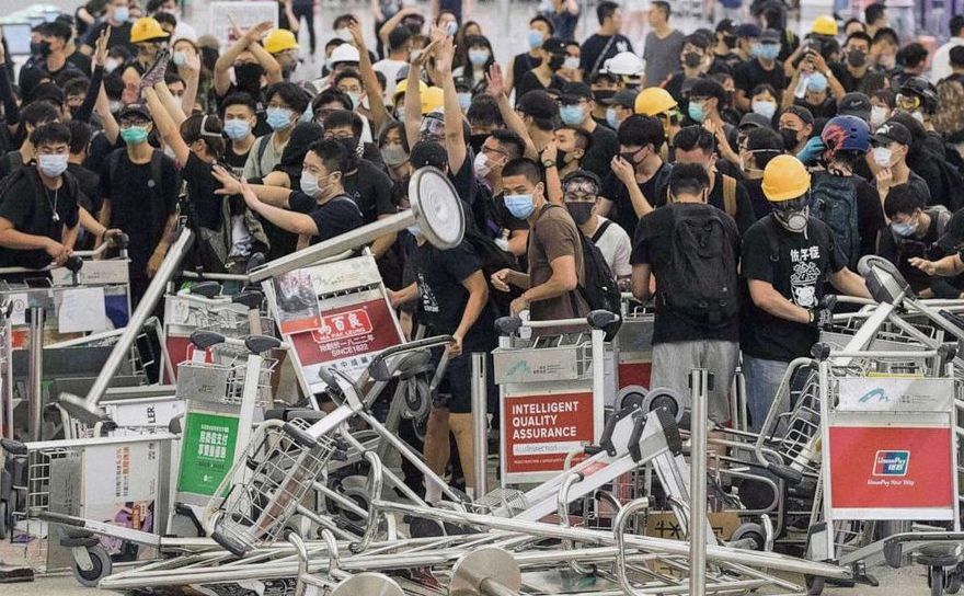 Manifestanţii ridică o baricadă în timpul ciocnirilor cu poliţia la Aeroportul Internaţional din Hong Kong, 13 august 2019