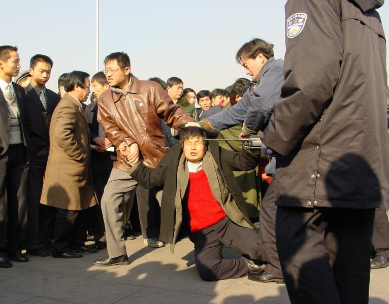 Securişti în civil arestează un practicant Falun Gong în Piaţa Tiananmen din Beijing, 31 decembrie 2000 (Minghui.org)