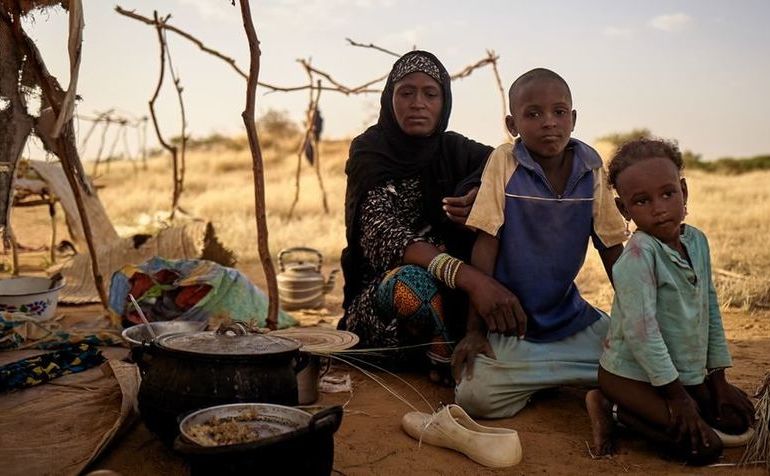 O familie strămutată stă în faţa unui cort într-o tabără neoficială din Bagoundié, Mali