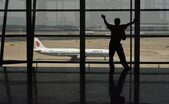 Un bărbat se uită la un avion prin fereastra aeroportului internaţional din Beijing. (Greg Baker/AFP/Getty Images)