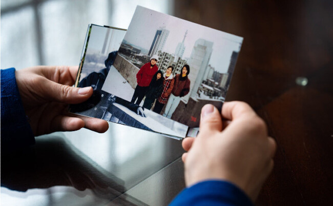 Steven Wang, dansator principal al Shen Yun, priveşte o fotografie cu mama şi surorile sale, în casa sa din statul New York, la 31 martie 2023. (Samira Bouaou/The Epoch Times)