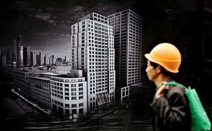 Un muncitor trece pe lângă un panou publicitar care anunţă un nou proiect imobiliar în Shanghai