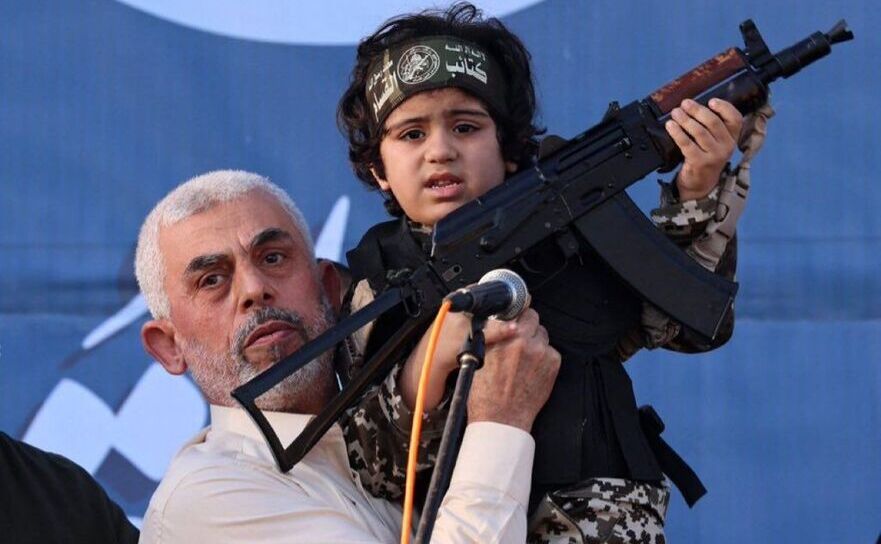 Yahya Sinwar (st), liderul palestinian al Hamas din Fâşia Gaza, ţinând în braţe un copil îmbrăcat în costum de soldat şi purtând o armă, la un miting al susţinătorilor săi, mai 2021, în oraşul Gaza.