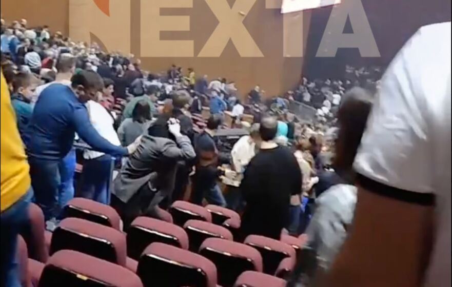 Un bărbat în pulover albastru şi blugi împinge înapoi pe culoarul dintre scaune o femeie care se îndrepta spre ieşire (Screenshot - X - Nexta)
