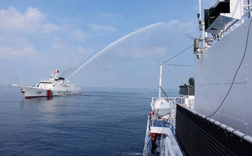 O navă a Gărzii de coastă chineze atacând cu tunuri cu apă o navă a Gărzii de coastă filipineză