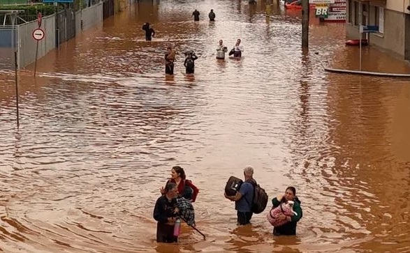 Oamenii merg pe o stradă inundată în cartierul Navegantes din Porto Alegre, statul Rio da Grande, Brazilia, 4 mai 2024.