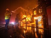 Un pompier se luptă cu incendiul Palisades, care arde casele de pe Pacific Coast Highway pe fondul unei furtuni puternice în Los Angeles, 8 ianuarie 2024 (Getty Images)