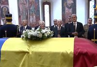 La slujba de înmormântare a lui Ion Iliescu, premierul Ilie Bolojan, al cărui guvern a organizat funeraliile de stat, a stat în al doilea rând, 7 august 2025 (YouTube - Screenshot)